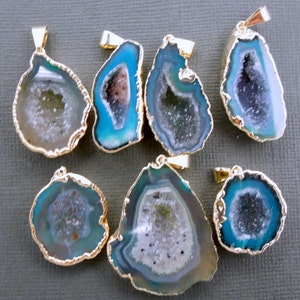 May include: Seven agate pendant charms with gold-toned metal settings. The agate is a light blue color with a white and gray crystal pattern inside. The charms are various shapes and sizes.