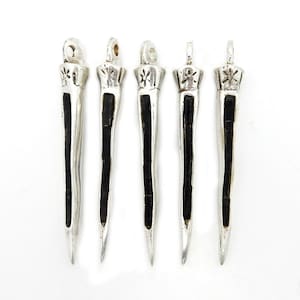 May include: Five silver pendants with black accents. Each pendant is shaped like a long, thin spike with a star-shaped design at the top.