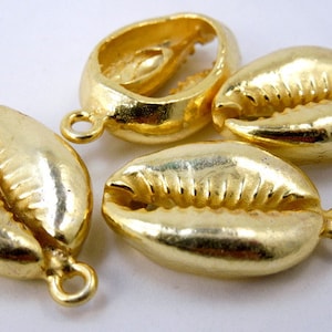 May include: Four gold-coloured cowrie shell charms with a loop for attaching to jewellery or other crafts.