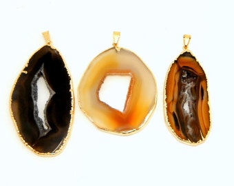 May include: Three agate pendants with gold-colored edges and bails. The pendants feature natural patterns in shades of brown, black, white, and orange. The shapes vary, including a teardrop and a circular slice.
