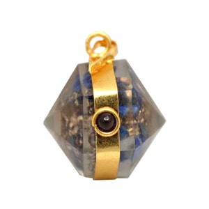 May include: A gold-toned pendant with a clear, faceted crystal orb. The orb is filled with small, blue and silver pieces. A small, dark red stone is set in the center of the orb.