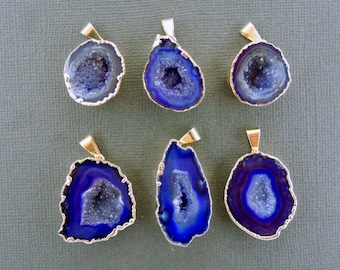 May include: Six blue and white geode pendants with gold-colored metal trim. The pendants have a natural, irregular shape and a gold-colored bail for hanging. The geodes have a crystalline interior.