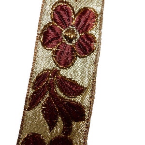 May include: Gold and burgundy trim with a floral design. The trim features a repeating pattern of flowers and leaves.