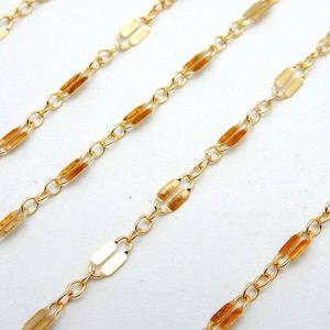 May include: Gold chain with a delicate, flat oval link design. The chain is made of metal and has a polished finish.