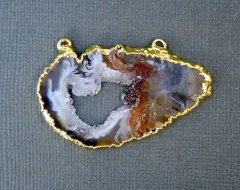 May include: A gold-rimmed agate pendant with a natural, white, brown, and gray agate slice. The agate has a large, open, heart-shaped center.