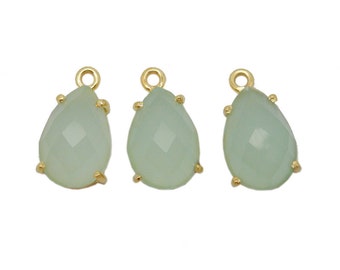 May include: Three gold-tone teardrop-shaped pendants with light green faceted glass stones.