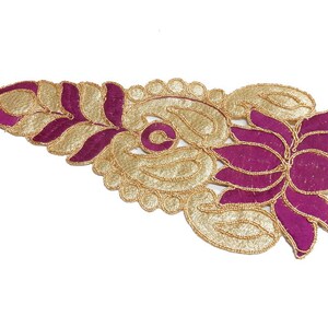 May include: An ornate, decorative textile in a leaf and floral design. The piece features a combination of gold and magenta colors, with intricate beaded detailing outlining the shapes. The design is set against a white background.