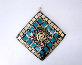 Puede incluir: Un colgante cuadrado con un diseño geométrico con piedras turquesa y rojas engastadas en metal dorado.