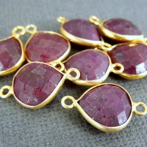 Puede incluir: Ocho abalorios conectores de piedra preciosa de rubí en forma de lágrima chapados en oro. Cada abalorio tiene dos anillos de salto para sujetar a las joyas.