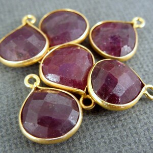 May include: Six gold-plated teardrop-shaped ruby gemstone pendants. Each pendant has a small loop at the top for attaching to jewelry.