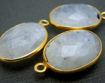 Può includere: Tre ciondoli ovali in pietra di luna bianca con montature in metallo dorato. Ogni ciondolo ha un anello per attaccarlo a una catena o un cordino.