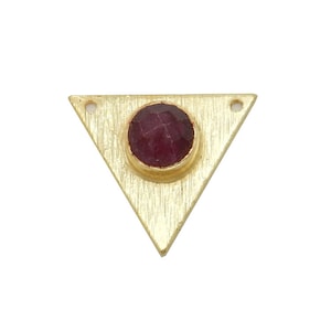 May include: Gold triangle pendant with a red gemstone in the centre.