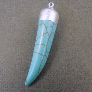 May include: A turquoise blue pendant shaped like a tooth with gold veins and a silver cap at the top.