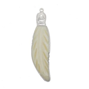 May include: A white carved feather pendant with a silver bail. The feather is detailed with a carved pattern.