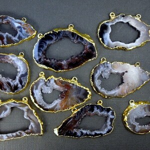 Puede incluir: Nueve rebanadas de &aacute;gata con bucles de metal dorado. Cada rebanada tiene una forma natural irregular con un gran centro abierto. El &aacute;gata es una mezcla de blanco, marr&oacute;n y negro.