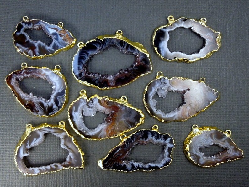 Puede incluir: Nueve rebanadas de &aacute;gata con bucles de metal dorado. Cada rebanada tiene una forma natural irregular con un gran centro abierto. El &aacute;gata es una mezcla de blanco, marr&oacute;n y negro.