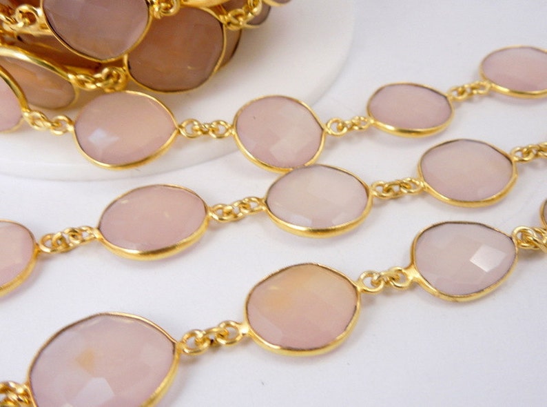 May include: A collection of Rose Pink Chalcedony Gold Plated Bezel Station Connector Chain Per Foot on white surface for reference.