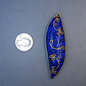 Op de afbeelding: Een blauwe en gouden hanger met een moza&iuml;ekontwerp. De hanger heeft de vorm van een traan en heeft rode accenten.