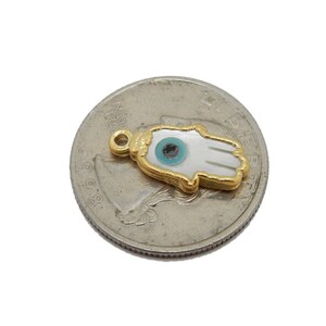 May include: Gold-plated charm with a white hamsa hand design and a blue evil eye. The charm is a popular symbol of protection and good luck.