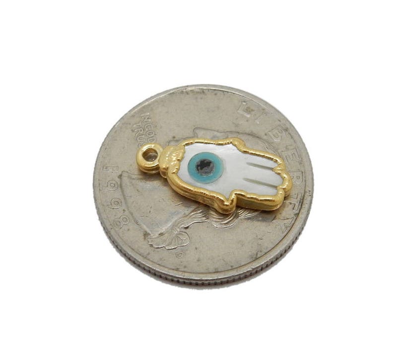 May include: Gold-plated charm with a white hamsa hand design and a blue evil eye. The charm is a popular symbol of protection and good luck.