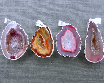 May include: Four agate geode pendants with silver settings. The geodes are cut in half to reveal the crystal formations inside. The geodes are various shades of brown, red, and white.