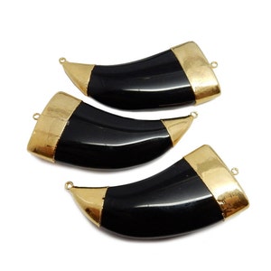 Op de afbeelding: Drie zwarte hoornvormige hangers met gouden accenten. De hangers hebben een gladde, gepolijste afwerking en zijn perfect om een ​​toets van stijl toe te voegen aan sieradenprojecten.