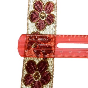May include: Gold and burgundy floral trim with a ruler measuring 1 inch (2.5 cm) in length.