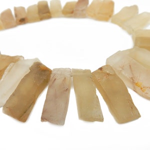 May include: A necklace made of translucent, light brown, rectangular stones. The stones are arranged in a circle and have a slightly irregular shape.
