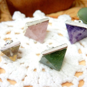 K&ouml;nnte beinhalten: Vier silberne pyramidenf&ouml;rmige Anh&auml;nger mit verschiedenen farbigen Edelsteinen. Die Anh&auml;nger sind aus Silber und haben eine glatte, polierte Oberfl&auml;che. Die Edelsteine sind rosa, lila, gr&uuml;n und braun.