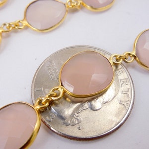 May include: A collection of Rose Pink Chalcedony Gold Plated Bezel Station Connector Chain Per Foot on top of quarter on white surface for reference.