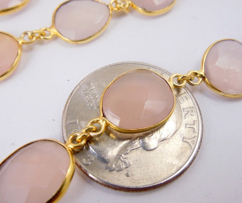 May include: A collection of Rose Pink Chalcedony Gold Plated Bezel Station Connector Chain Per Foot on top of quarter on white surface for reference.