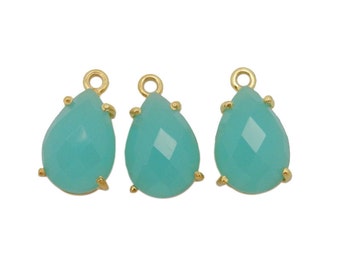 May include: Three gold teardrop-shaped charms with a light turquoise gemstone. The charms have a smooth, faceted surface and are perfect for jewelry making.