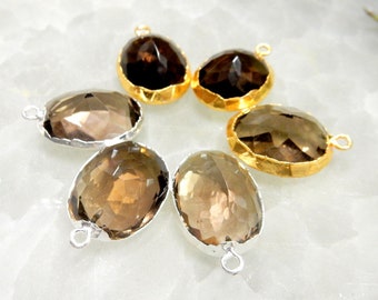 May include: Six oval-shaped smoky quartz gemstone pendants with gold and silver settings. The pendants are arranged in a circle on a white surface.