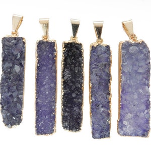 May include: Five purple and gold crystal pendants. Each pendant is a rectangular shape with a gold trim and a purple crystal center. The crystals are all different shapes and sizes.