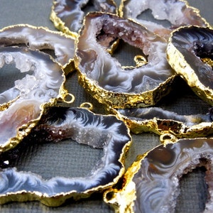 Puede incluir: Una colecci&oacute;n de rodajas de &aacute;gata con bordes chapados en oro. El &aacute;gata es una piedra natural con una variedad de colores y patrones, incluyendo blanco, marr&oacute;n y negro. Las rodajas son de diferentes tama&ntilde;os y formas, y tienen un acabado liso y pulido.