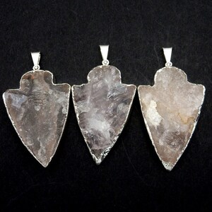 May include: Three silver arrowhead pendants with clear, translucent, light pink quartz crystals. The arrowheads are approximately 2 inches long.
