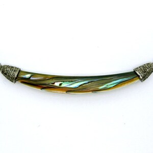 Puede incluir: Un colgante curvo de concha de abulón con tapas de extremo de plata engastadas con pequeños diamantes.