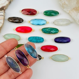 May include: Assortment of oval-shaped gemstone connector beads with silver and gold accents. The beads are in various colors, including red, green, blue, purple, and brown.