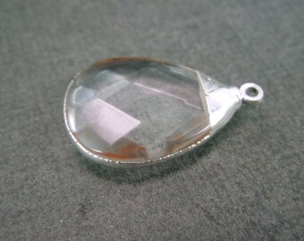May include: A clear glass teardrop pendant with a silver bezel setting and a silver loop for attaching a chain.