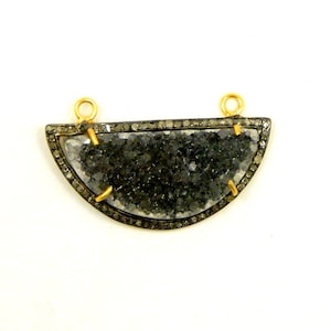 May include: A half-circle pendant with a black and white agate stone set in a silver frame with a diamond border. The pendant has two gold jump rings for attaching a chain.