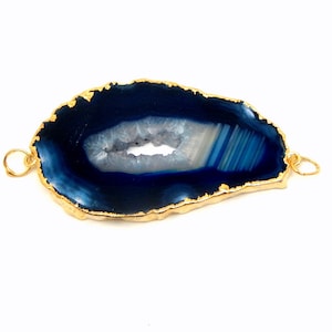 May include: A blue agate slice with a gold-plated edge and a hole for hanging. The agate has a natural, irregular shape and a white center.