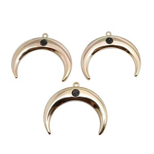 Op de afbeelding: Drie gouden halve maan bedels met zwarte glitter accenten. Elke bedel heeft een lus aan de bovenkant om aan sieraden te bevestigen.