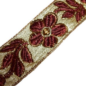May include: Gold trim with burgundy floral embroidery. This trim features a repeating pattern of flowers and leaves.