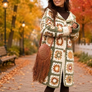 May include: A long-sleeved crochet cardigan featuring a multi-colored granny square pattern in shades of cream, olive green, brown, and orange. The garment has a button-down front and is paired with a brown circular crossbody bag with long fringe.