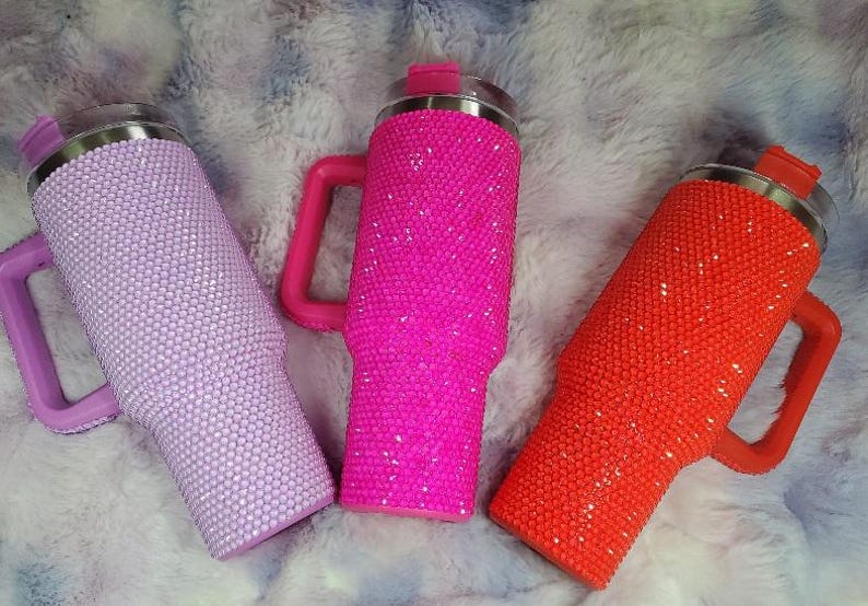 Pu&ograve; includere: Tre bicchieri isolanti ricoperti di strass scintillanti. I bicchieri sono nelle tonalit&agrave; lavanda, rosa acceso e arancione, ciascuno con manico e coperchio abbinati. I bicchieri sono progettati per mantenere le bevande fredde o calde.