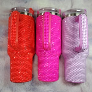 Pu&ograve; includere: Tre bicchieri tempestati di strass rossi, rosa acceso e lavanda. Ogni bicchiere ha un manico abbinato ed &egrave; ricoperto di strass scintillanti. I bicchieri hanno coperchi trasparenti e un bordo argentato.