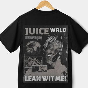 May include: Black t-shirt featuring a graphic design with the text "JUICE WRLD" and "LEAN WIT ME!". The design includes a portrait of a person and other text. The shirt is hanging on a wooden hanger.