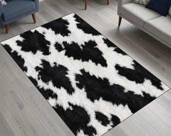 May include: A rectangular rug with a black and white cowhide pattern. The rug features irregular black patches against a white background, creating a bold, animal-inspired design. The rug is placed on a light grey wooden floor.