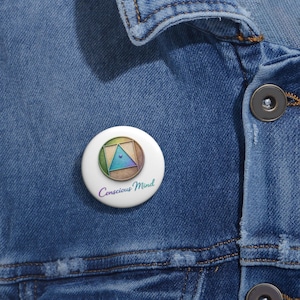 May include: A white button pin with a geometric design featuring a triangle and square in shades of green, blue, and brown. The pin has the words "Conscious Mind" in a gradient font.