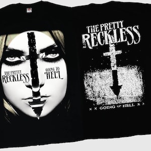 May include: Black t-shirts featuring the band "The Pretty Reckless." One shirt displays a woman's face bisected by a cross, with "Going to Hell" text. The other shirt has a cross with an arrow and the same text.